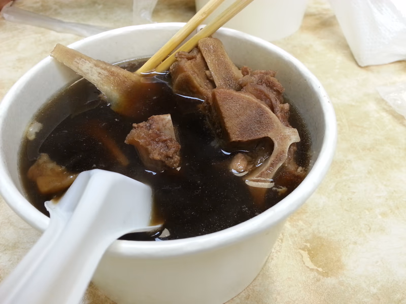 A bowl of soup with chopsticks and a spoon
